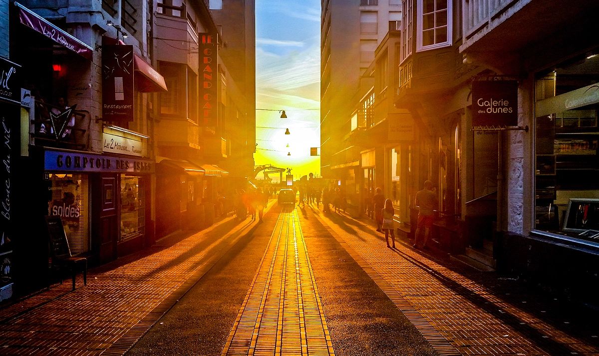 qtq80-0JmhpP A street with many buildings and a sun setting